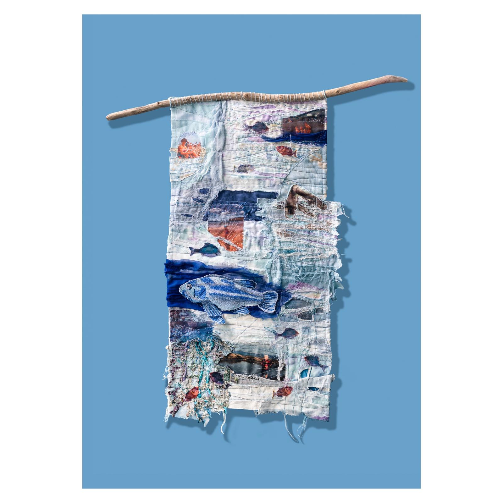 Tidelines: a tall hand-dyed hanging in blues, hung from driftwood, with photo-transferred fish and frayed, unravelling edges.